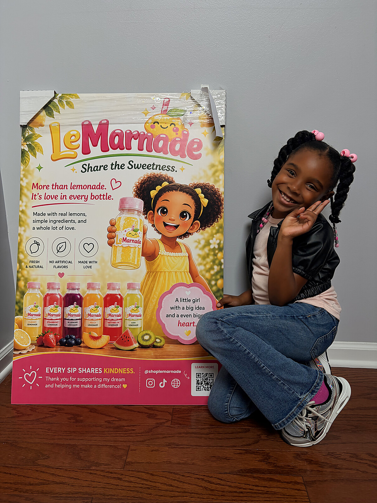Amaria, founder of LeMarnade, kneeling beside her LeMarnade poster